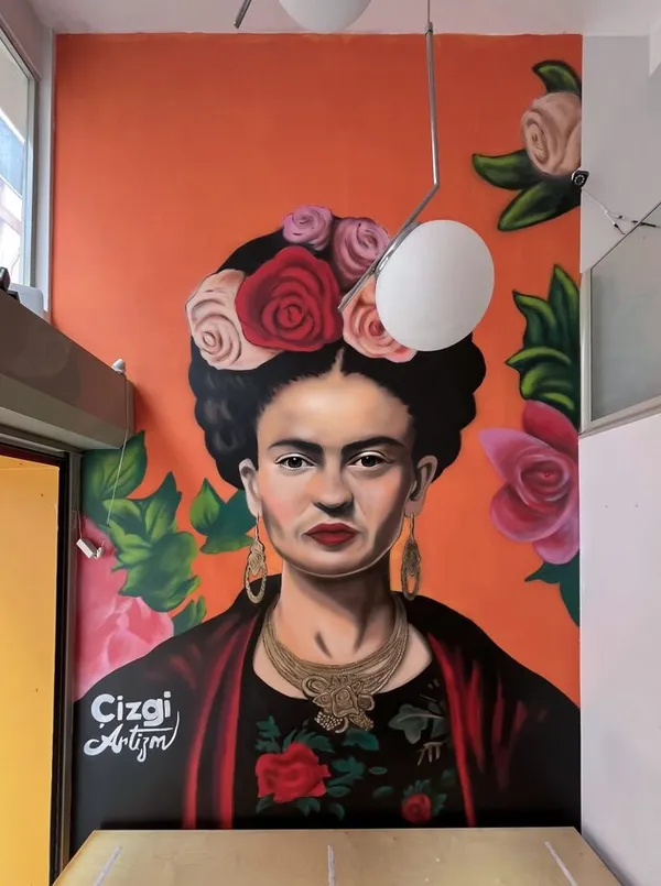 Turuncu zeminde güllerle çevrili Frida Kahlo portresi iç mekan duvar resmi